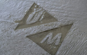 Logo Universiteit Maastricht in betonnen vloer