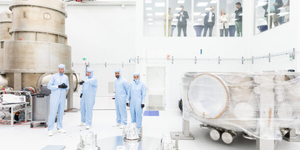 Minister en anderen in de cleanroom van ETpathfinder met de installatie op de achtergrond